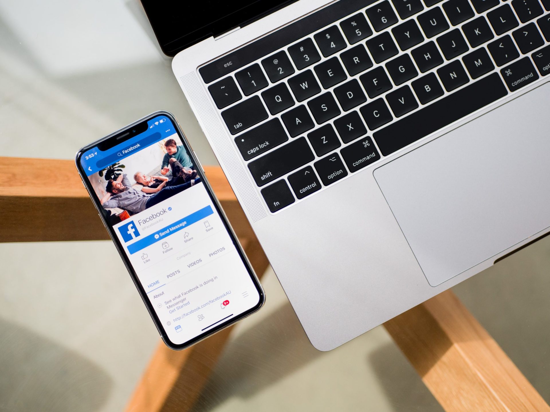 facebook on phone next to a laptop