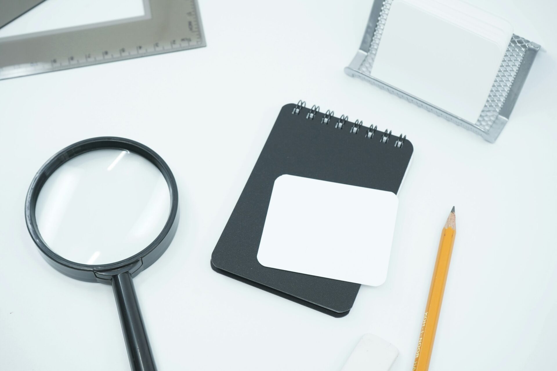 magnifying glass on table with pencil and notebook